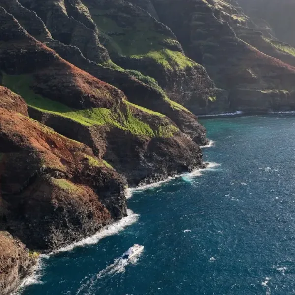 Rugged coastal cliffs with green patches and blue ocean waves below.