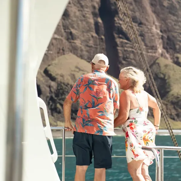 Elderly couple on a boat enjoying the view of cliffs over the ocean.