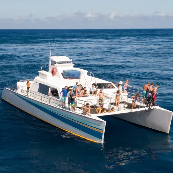A boat with people enjoying a sunny day on the ocean.